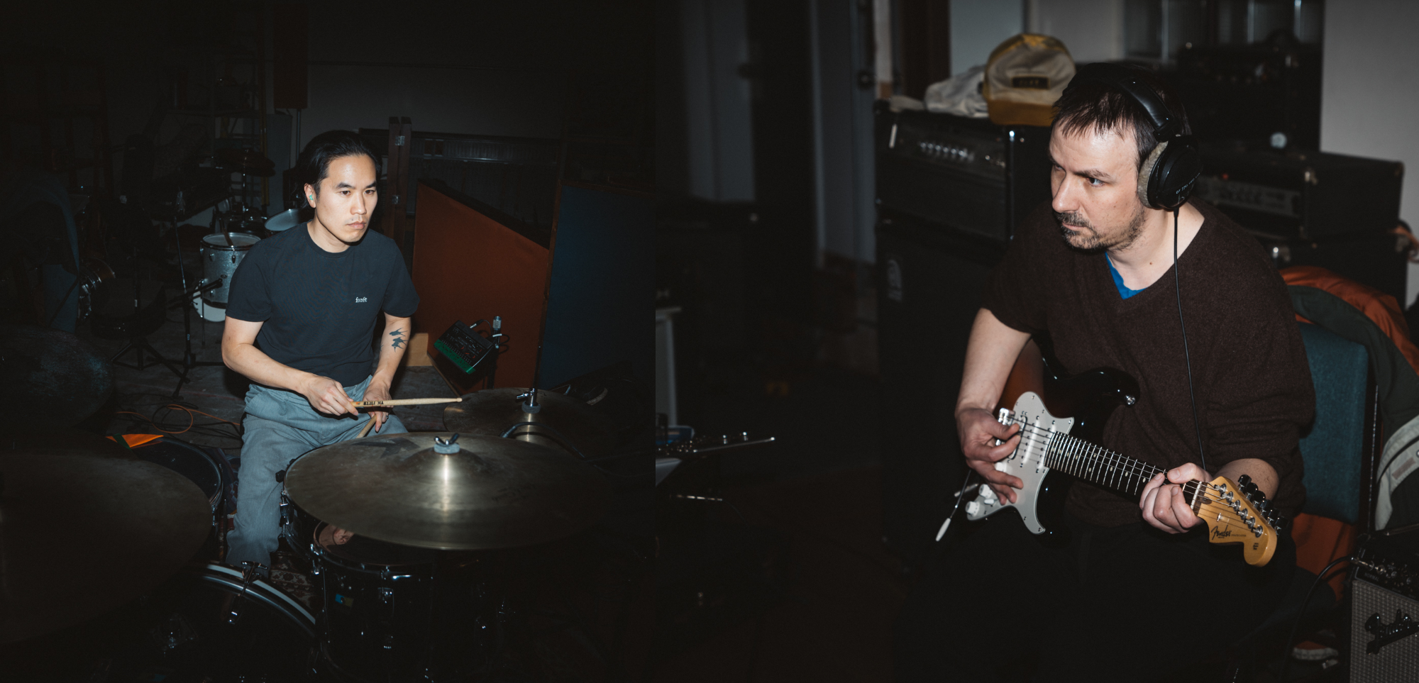 A drummer and guitarist playing music in the studio while recording
